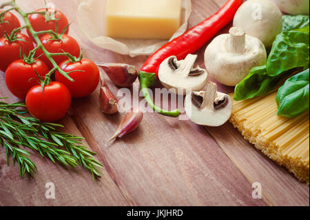 Montón de spaghetti italiano closeup con champiñones y tomates en una rústica cocina en una mesa de madera. En el modo de fondo, chef de tomate troceado para co