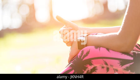 Atractivo deportivo anónimo mujer vistiendo smart watch mostrando Thumbs up después de la sesión de ejercicio físico Foto de stock
