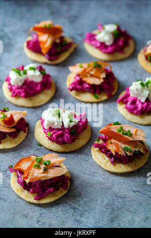 Blinis con remolacha, rábano picante, salmón ahumado en caliente y cabra chhese