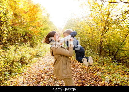 Hermosa joven madre con su hijo en el bosque de otoño. Foto de stock