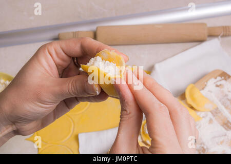 Vista de cerca de las manos de la mujer prepara para cocinar vareniki, albóndigas, pierogi de queso fresco o requesón una tradicional comida ucraniana. Rolling pi Foto de stock