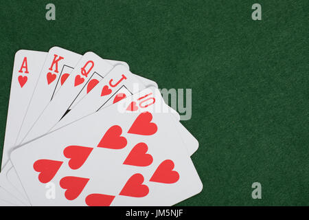 Mano de póquer ganadora con una escalera real de corazones dispuestos en la esquina de un tapete verde tabla con copia espacio en un concepto de juego Foto de stock