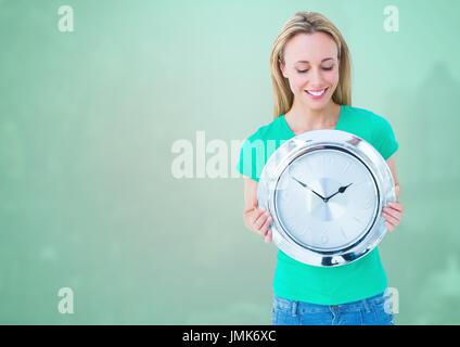 Compuesta Digital de Mujer sosteniendo el reloj delante de fondo verde Foto de stock