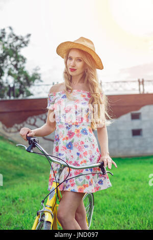 Retrato de hermosa chica rubia montando bicicleta en el parque