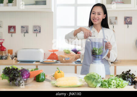 Batido de vegetales. Mujer Asiática hacer batidos verdes con Blender de casa en la cocina. Concepto de estilo de vida saludable comer crudo retrato de la hermosa joven