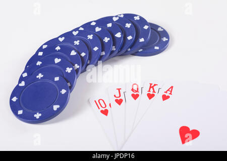 Conjunto de chips de juego redondo azul y naipes acomodado sobre fondo blanco. Foto de stock