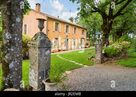 Antigua casa de campo de piedra rodeada de tranquilos jardines en el sur de Francia con el antiguo gatepost en primer plano