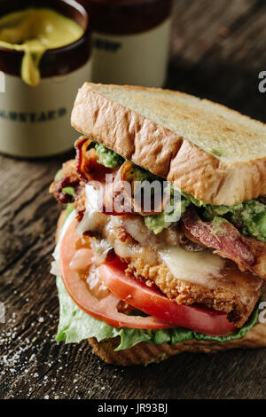 El pollo y el Aguacate BLT sándwich en superficie rústica