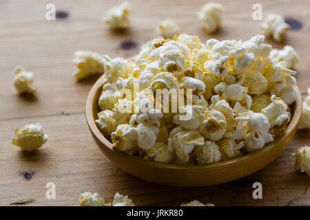 En un tazón de palomitas de maíz salado fresco sobre la mesa de madera