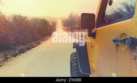 Jeep amarillo sobre unidad de aventura al aire libre, un estilo de vida activo de explorar el desierto y el país. Muestra los árboles, el camino y la vida en la vista trasera. Foto de stock
