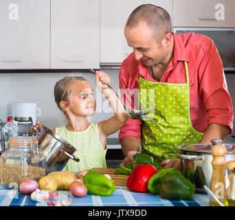 Niña padre ayudando a preparar la cena en el interior Foto de stock