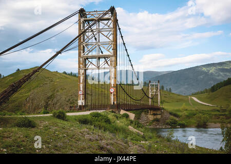 Puente colgante de madera sobre un río de montaña en lo alto de las montañas de Altai. Foto de stock
