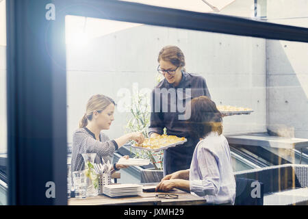 Dos mujeres empresarias canapés servidos durante el almuerzo de negocios fuera de la oficina