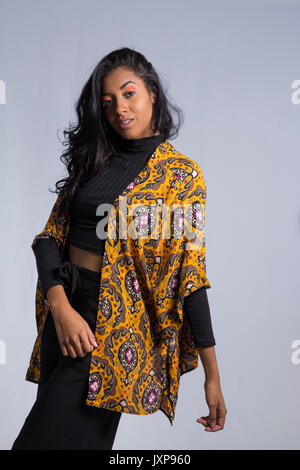 Elegante mujer posa para la foto. Brazos inclinados. Mujer afrodescendiente  lleva ropa negra y amarilla. Ella es brasileña. Maquillaje de color. La  moda. Sty Fotografía de stock - Alamy