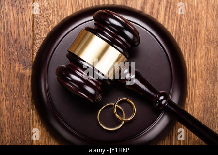 Un alto ángulo de visualización del concepto de divorcio con martillo y anillos de boda en un mostrador de madera Foto de stock