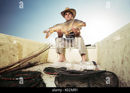 Pescador sosteniendo una gran carpa