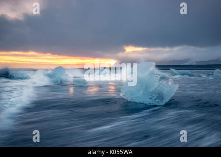 Bloque de hielo en la playa negra en la Laguna glaciar Jokulsarlon durante una puesta de sol, el este de Islandia, Europa
