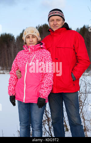 Sonriente pareja senior en ropa de abrigo de pie junto al aire libre en temporada de invierno Foto de stock