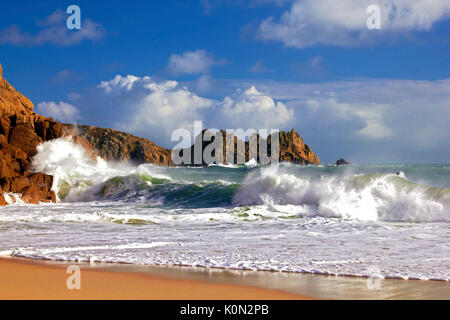 Una vista de porthcurno beach como las olas chocan contra los acantilados Foto de stock
