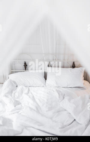 La cama blanca en la mañana a la luz vintage habitación de madera. Interior en color blanco Foto de stock
