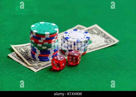 Casino de mesa verde con patatas fritas, dinero y cubos. Concepto de juego de poker Foto de stock