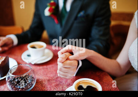 La foto de una pareja de novios cogidos de la mano en un pequeño café.