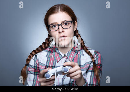 Nerd mujer con trenza jugando videojuegos con un Joypad Foto de stock