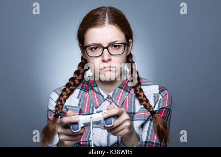 Nerd mujer con trenza jugando videojuegos con un Joypad Foto de stock