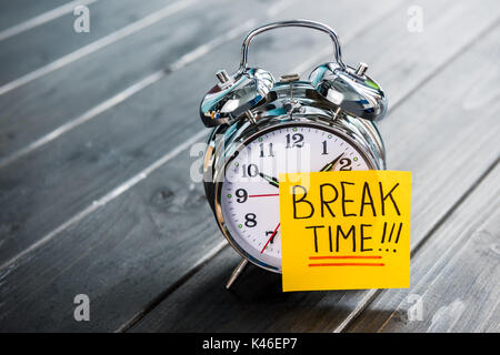 Cerca del reloj de alarma con mensaje Tiempo de pausa en el tablero de madera