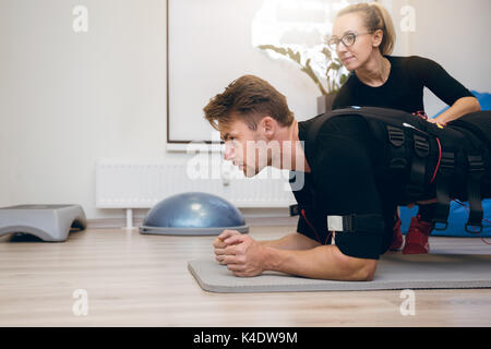Retrato del lado del deportista trabajando en el suelo, con entrenador personal Foto de stock