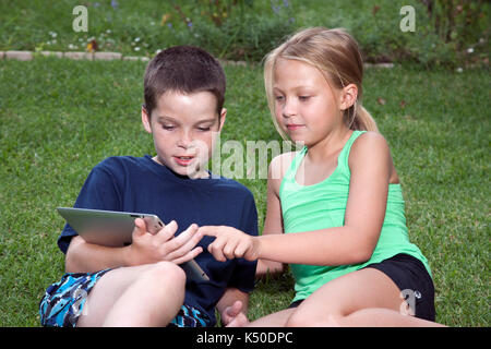 Dos niños jugando en un iPad Foto de stock