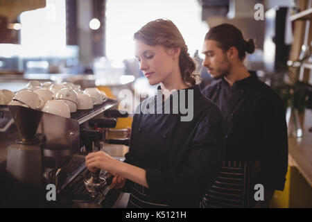 Los jóvenes camareros con cafetera expreso de pie en la cafetería. Foto de stock