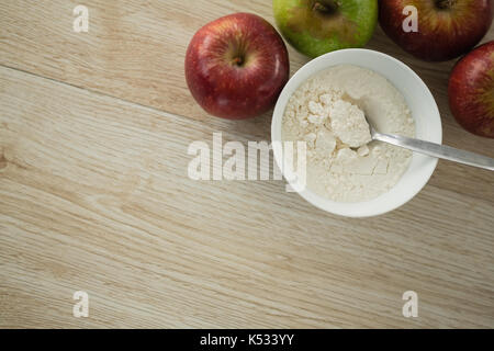Captura directamente encima de la harina en un tazón de manzanas de mesa de madera Foto de stock
