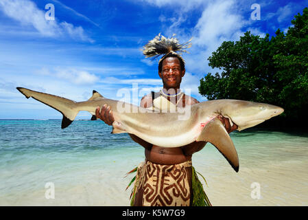 Tribu korafe folk, hombre con tapa típica ropa hecha de corteza de árbol  posee un cautivo blacktip reef (carcharhinus Fotografía de stock - Alamy