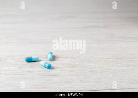 Tres cápsulas de medicina azul brillante en la tabla Foto de stock