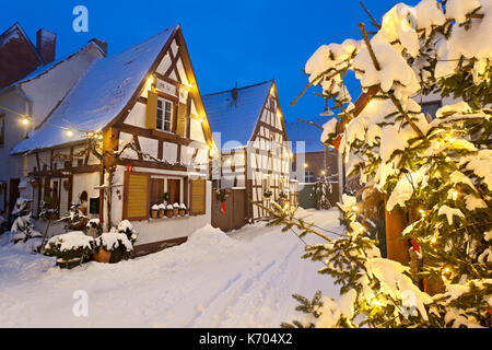 Una antigua calle de la aldea de casas con entramado de madera y luces en la noche de Navidad durante las nevadas en lachen, Neustadt an der weinstrasse, Alemania.