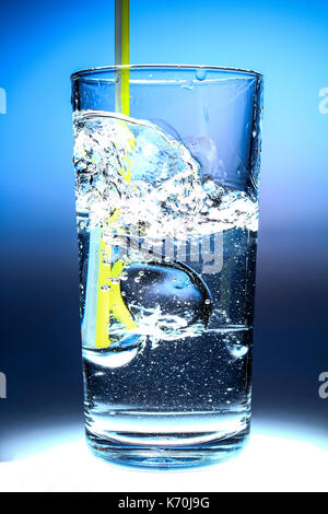 Refrescantes vaso de agua con una paja y burbujas aisladas sobre un fondo azul.