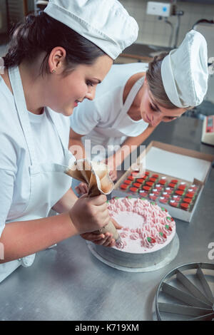 Las mujeres confitero poniendo crema pastel