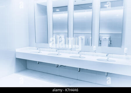Limpie el interior moderno nuevo inodoro Fregadero fila el tono de color azul. el agua a la ducha de mano en el baño. Foto de stock