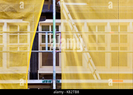 Andamios con redes de seguridad amarilla durante la renovación de un edificio en Rotterdam, en los Países Bajos Foto de stock