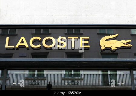 Lacoste firmar en un almacén. Lacoste es una empresa que vende ropa francesa de alta gama de perfumes, ropa, calzado, artículos de cuero, y la más famosa polo s Foto de stock
