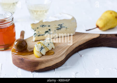 Servido con queso azul y miel de pera fresca en junta de corte rústico, tabla de quesos Foto de stock