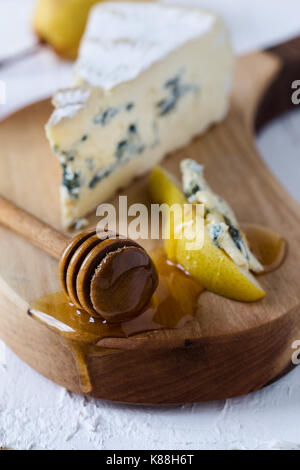 Servido con queso azul y miel de pera fresca en junta de corte rústico, tabla de quesos Foto de stock