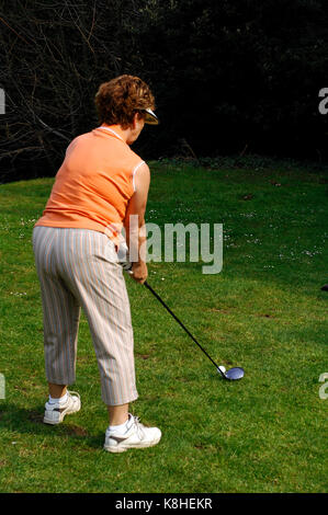 Una anciana jugando un tiro en una ronda de golf. golf en la jubilación o en etapas posteriores de la vida, participar en deportes y mantenerse activo, Foto de stock