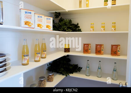 Un paseo en la despensa de la cocina modelo con jarras, botellas de vino y cajas de alimentos. Foto de stock