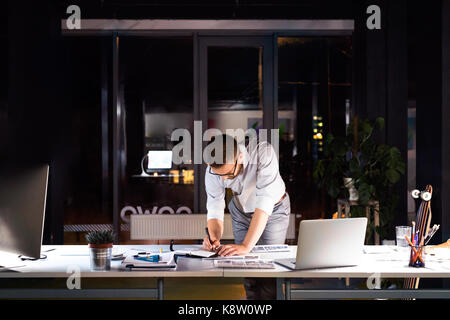 El empresario en la oficina trabajando hasta tarde en la noche. Foto de stock