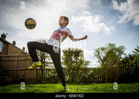 Chico jugando al fútbol en casa Foto de stock