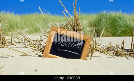 Bienvenidos escrito en una pizarra en la playa en el verano Foto de stock