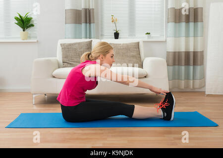 Mujer joven haciendo ejercicio en la sala de estar Foto de stock