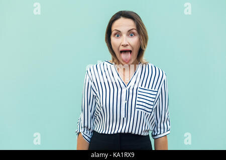 Felicidad empresaria, mirando a la cámara con ojos grandes y lengua fuera cubierta sobre fondo azul claro, Foto de estudio